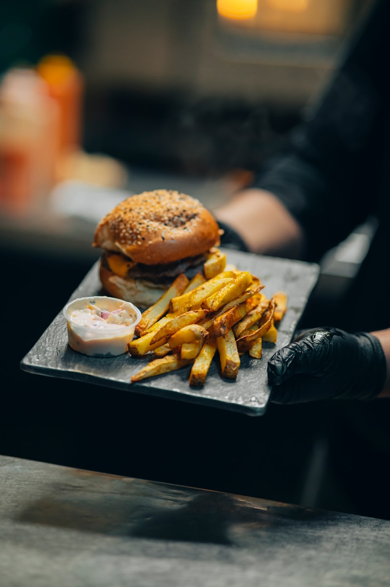 A person holding a tray with a hamburger and french fries